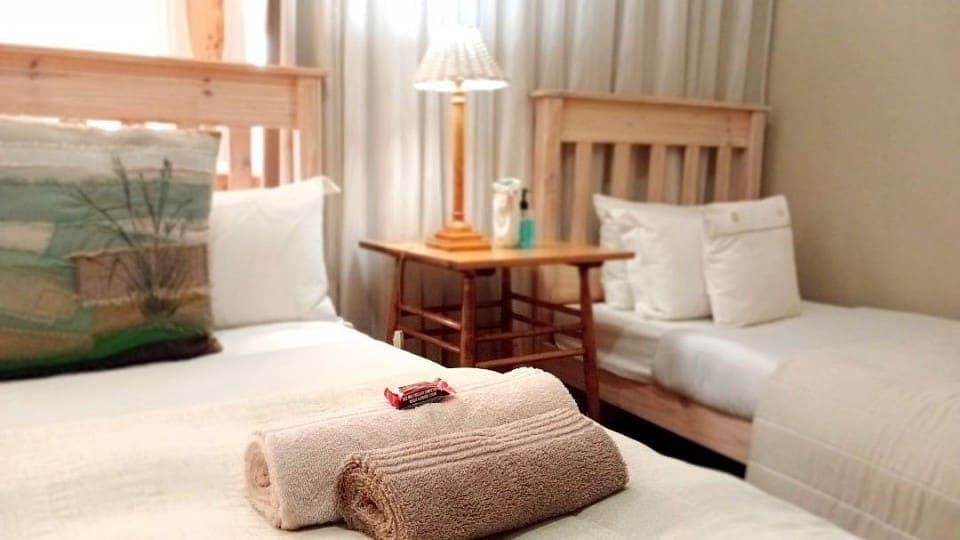 Calamus: two of the three beds, with rolled towels, a scatter cushion and a bedside lamp