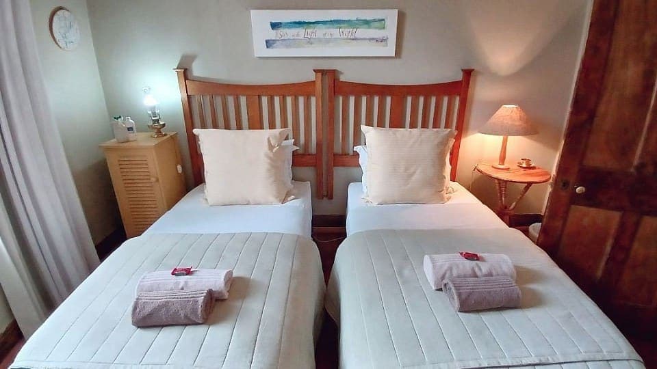 Camphire: two beds beneath a framed print, with rolled towels laid out on the covers