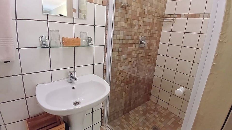 Frankincense: the en-suite shower and pedestal basin, tiled in white with brown mosaic accents