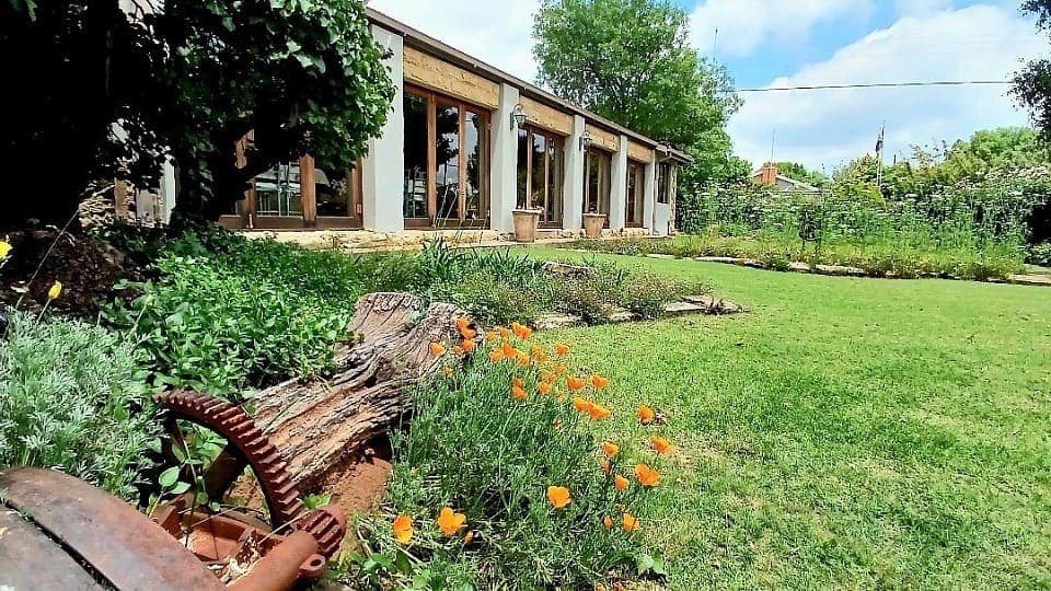 House Beautiful seen across the lawn, with orange poppies flowering in the foreground