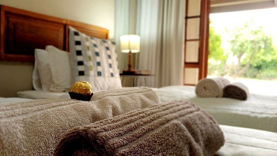 Myrrh: two beds with rolled towels, the garden visible through the French doors