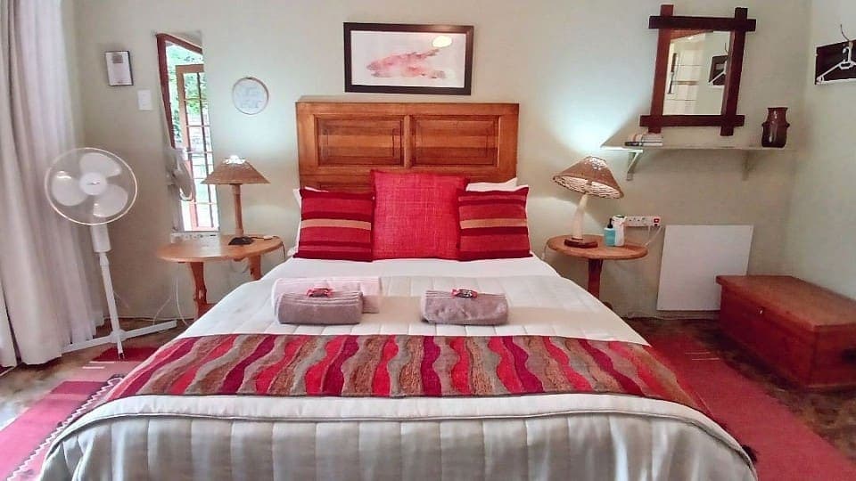 Saffron: the double bed with red and striped cushions against a carved wooden headboard