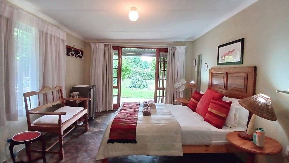 Saffron: the double bed and wooden bench, with the French doors open onto the lawn