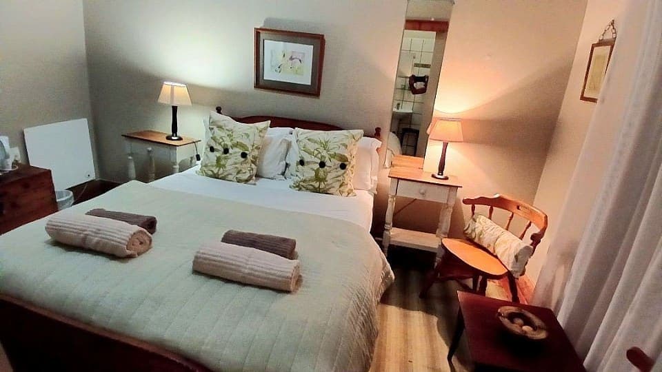 Spikenard: the double bed with floral cushions and a wooden headboard, on a yellow-painted wall