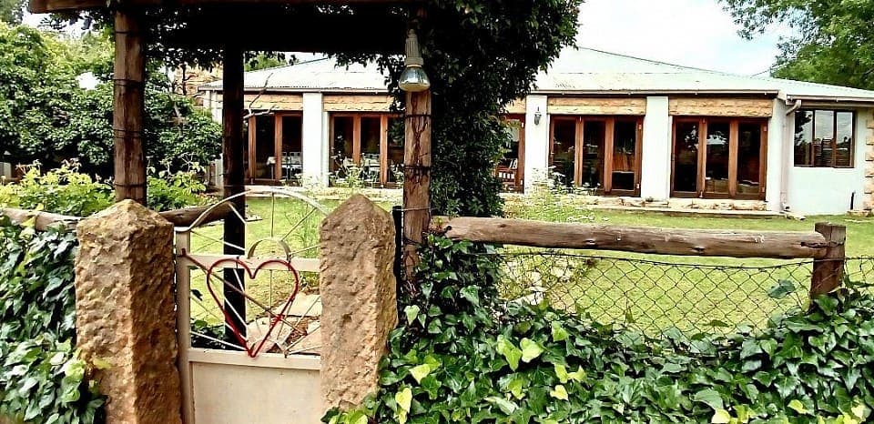 The entrance gate to House Beautiful, with a heart worked into the wire and the house behind