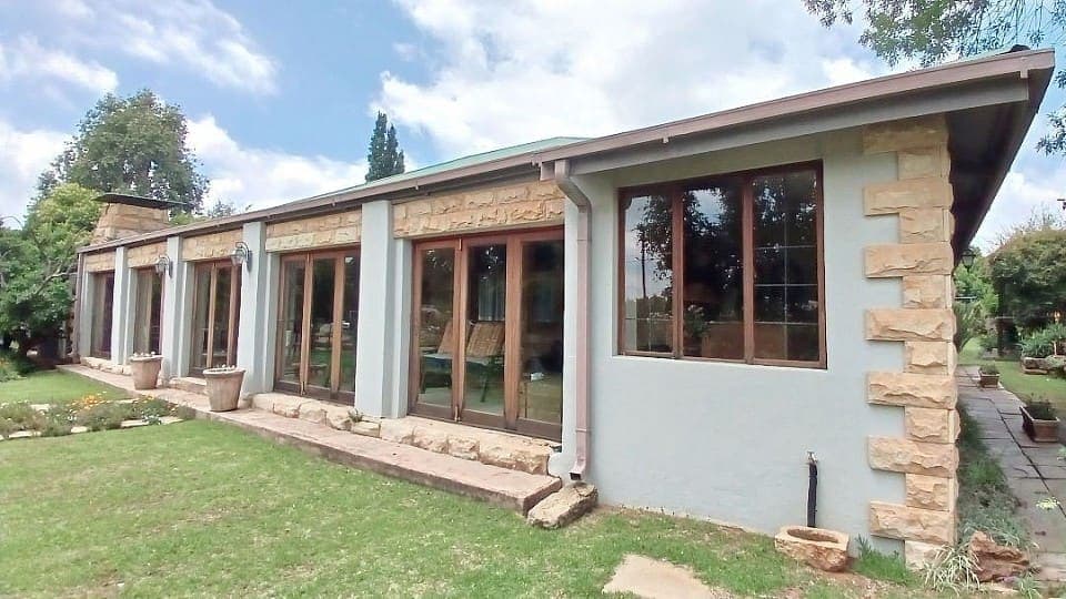 The glass and sandstone frontage of House Beautiful with the garden in front of it