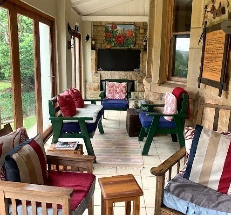 The covered patio lounge at House Beautiful, with deep couches around a stone fireplace and television